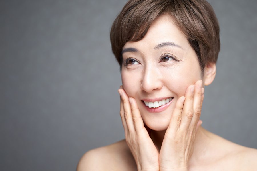 A middle-aged Japanese woman who puts her hands on her cheeks wi